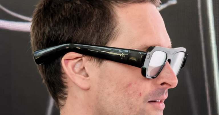 Side profile of a man wearing Snap's black AR Specs glasses, showing the bulky arm and ear fit